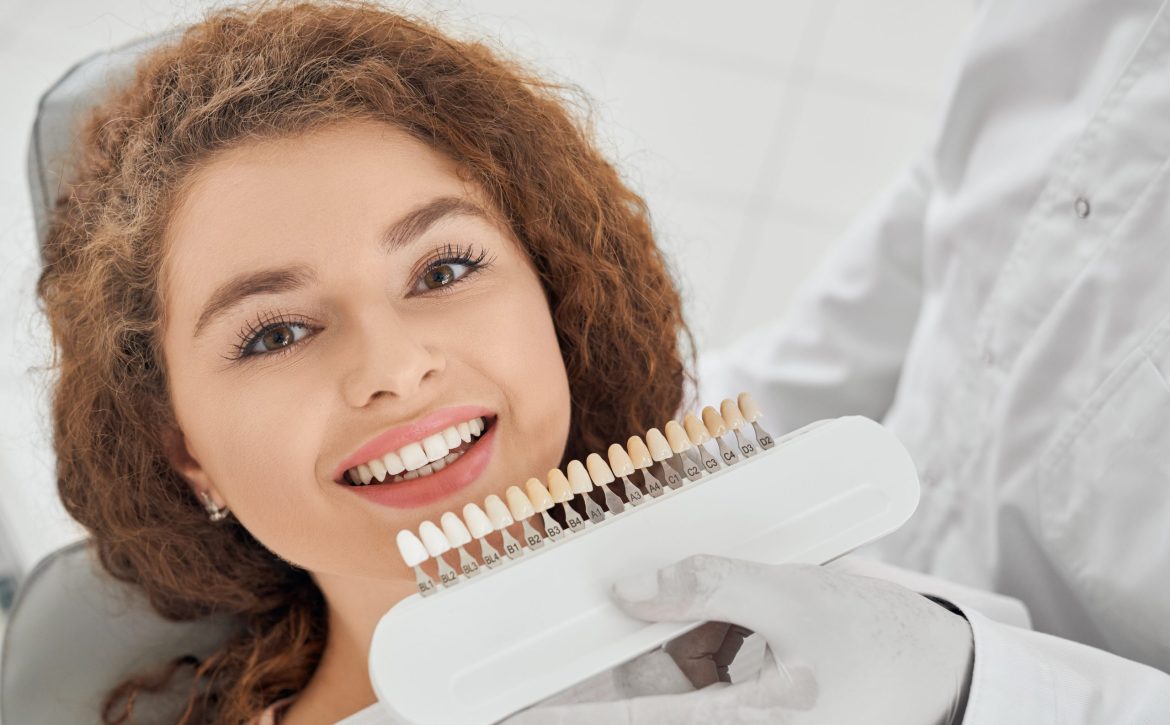 Woman smiling while male dentist keeping teeth color range